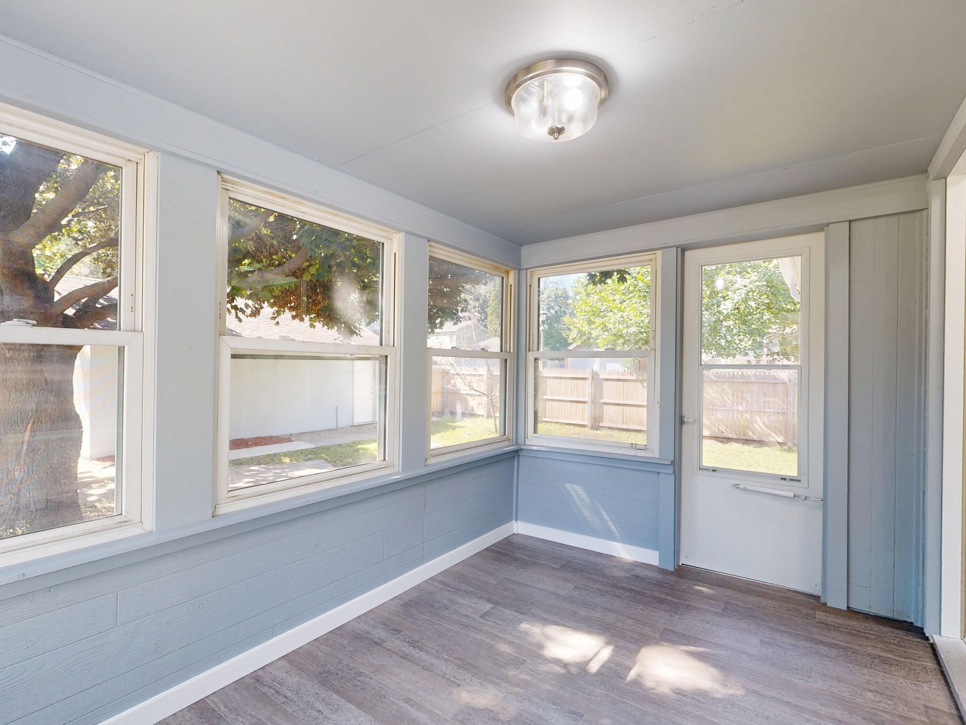 Spacious sunroom with large windows, natural light, and modern flooring.